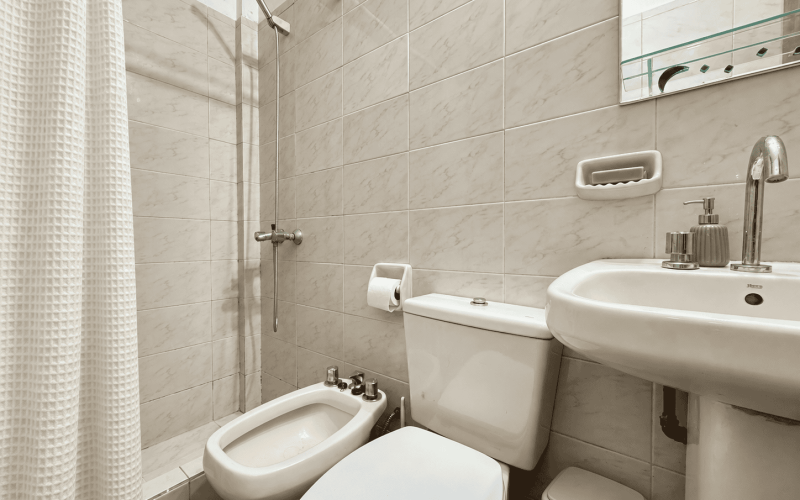 Baño pequeño renovado con cortina marfil